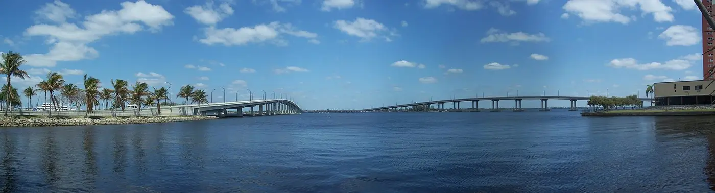 Panorama of the Edison Bridge crossing the wide Caloosahatchee River with palms on the shore